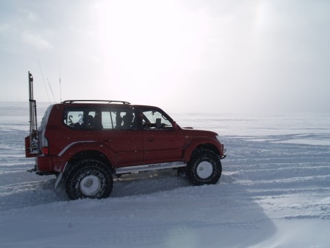 Gudmundur on the red Land Cruiser speeds on...